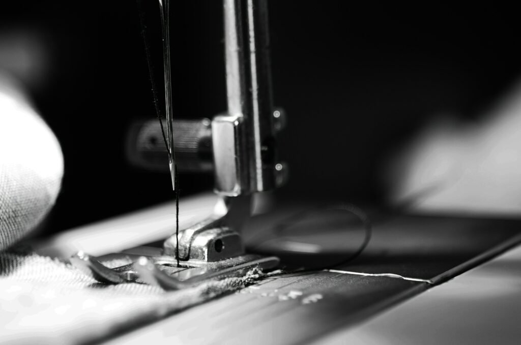 Close-up of industrial sewing machine stitching garment fabric